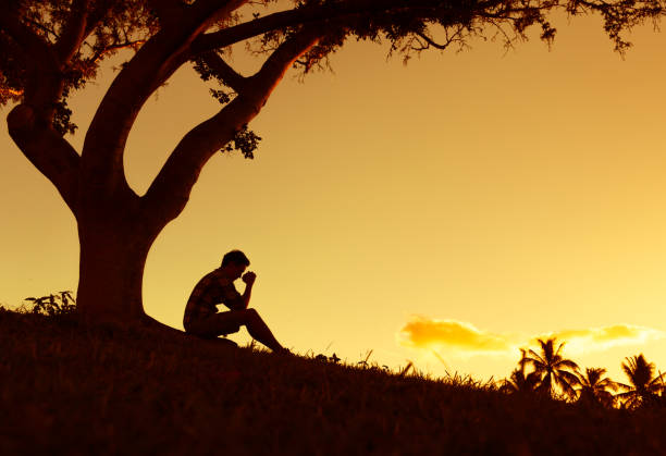 Silhouette Of Sad Man Sitting Under The Tree.